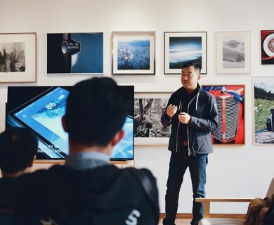 Man giving a presentation in a modern art gallery setting, engaging audience.