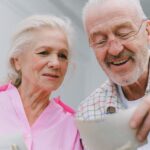 Happy senior couple enjoying old photographs and sharing memories together.