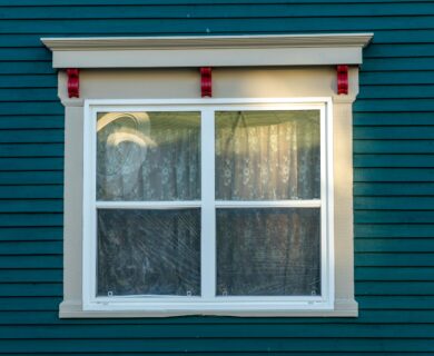 Window with a decorative trim on a teal building.